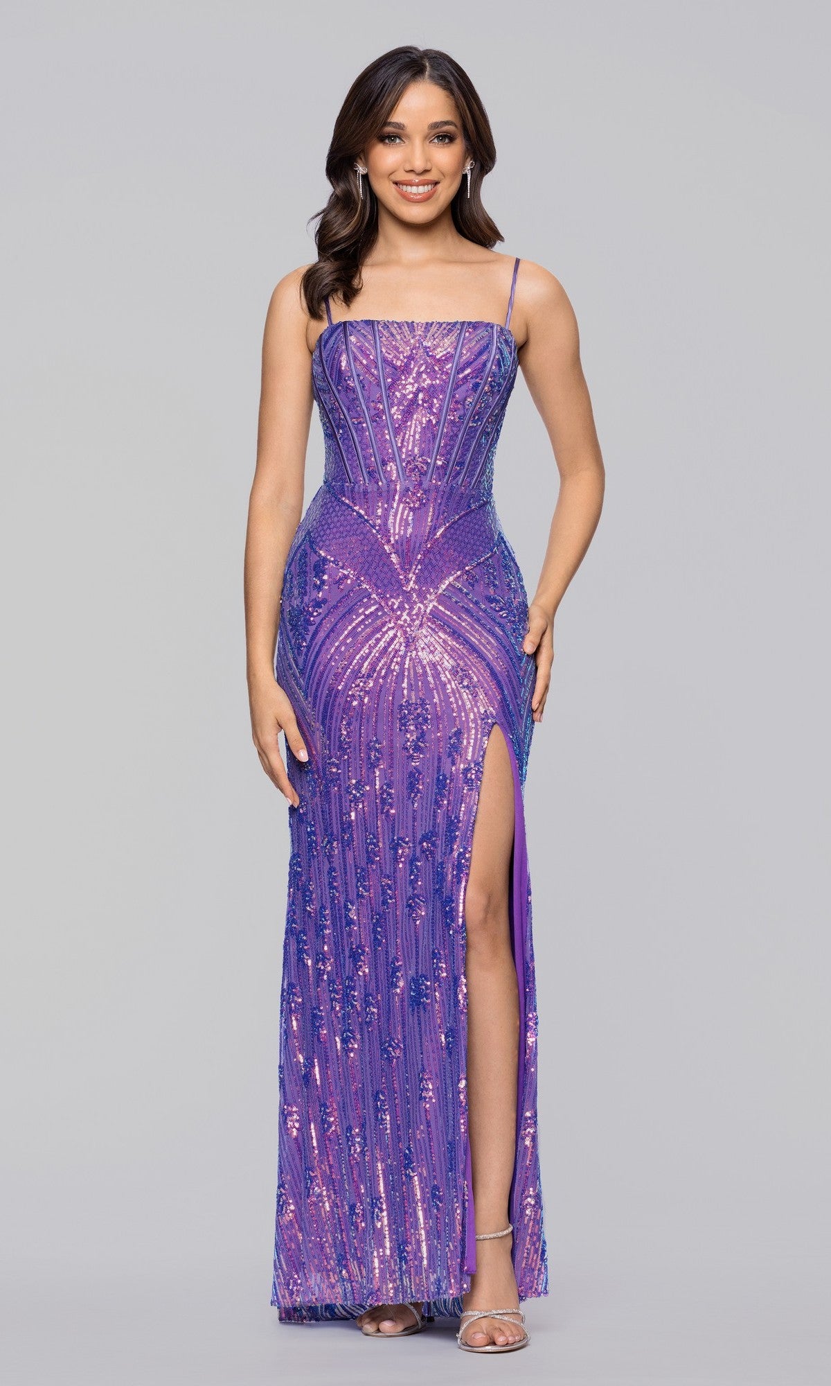 A woman smiles in the Blondie Nites 6048BN long prom dress, a fitted, floor-length purple gown with sequins, thin straps, and a thigh-high slit, against a plain gray background.
